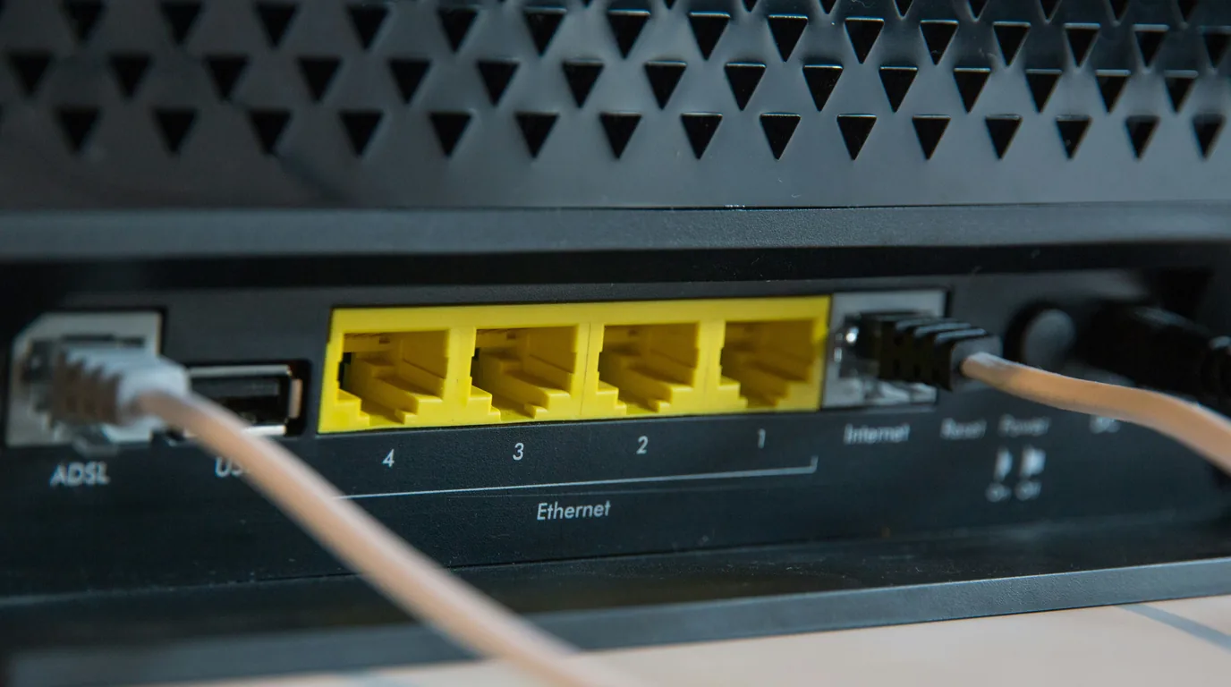 The rear panel of a home router: four yellow Ethernet ports numbered 1 to 4 beside ADSL, USB and Internet.